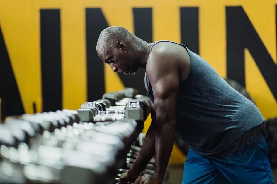 Choosing dumbbells from a rack at the gym to start a free training plan