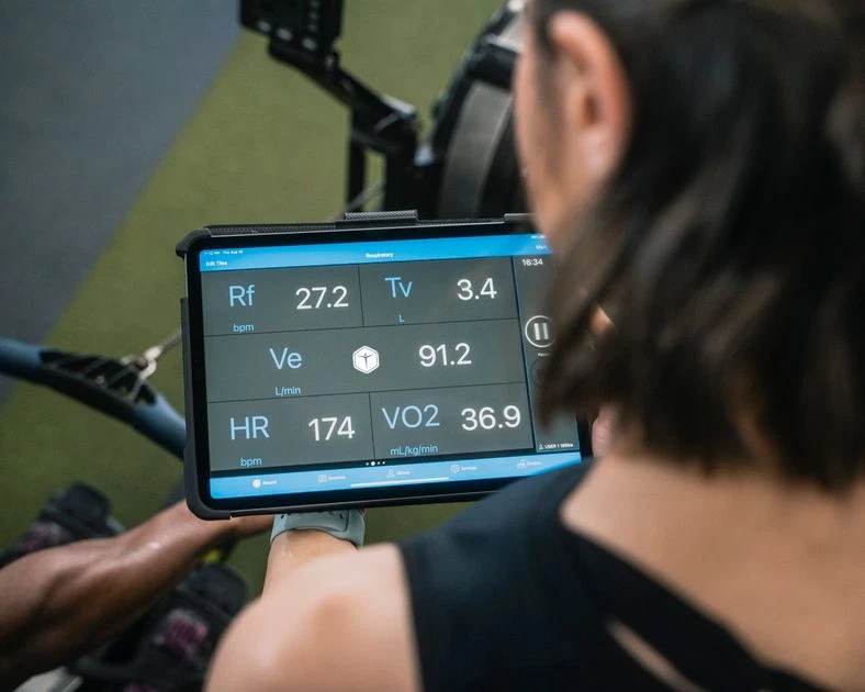 Reviewing a personalized workout plan and training metrics on a tablet at the gym