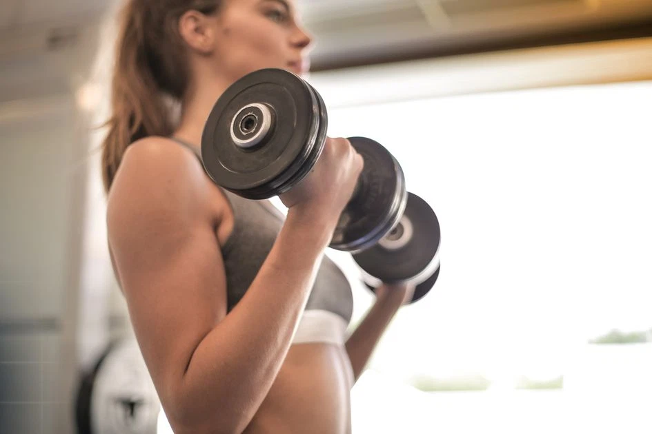 Woman training with a dumbbell in the gym on a get-fit toning program